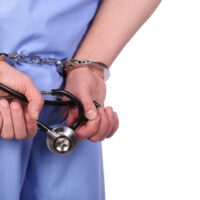 Doctor with stethoscope in handcuffs isolated on white