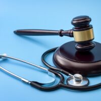 Healthcare legislation and regulation, medical malpractice decision and health care injury personal attorney concept with gavel and stethoscope isolated on blue background
