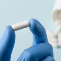 Pill in lab scientist hand. Healthcare drug substance analysis c Pill in lab scientist hand. Healthcare drug substance analysis c
