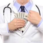 A doctor putting money in his pocket