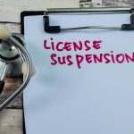 Concept of License Suspension write on paperwork with stethoscope isolated on wooden background. Concept of License Suspension write on paperwork with stethoscope isolated on wooden background.