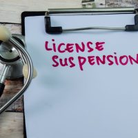 Concept of License Suspension write on paperwork with stethoscope isolated on wooden background.
