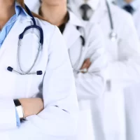 Group of modern doctors standing as a team with arms crossed in hospital office. Physicians ready to examine and help patients.